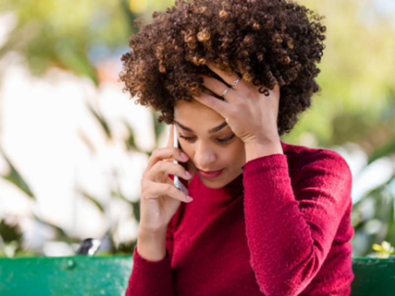 woman holding head in hand, talking on phone