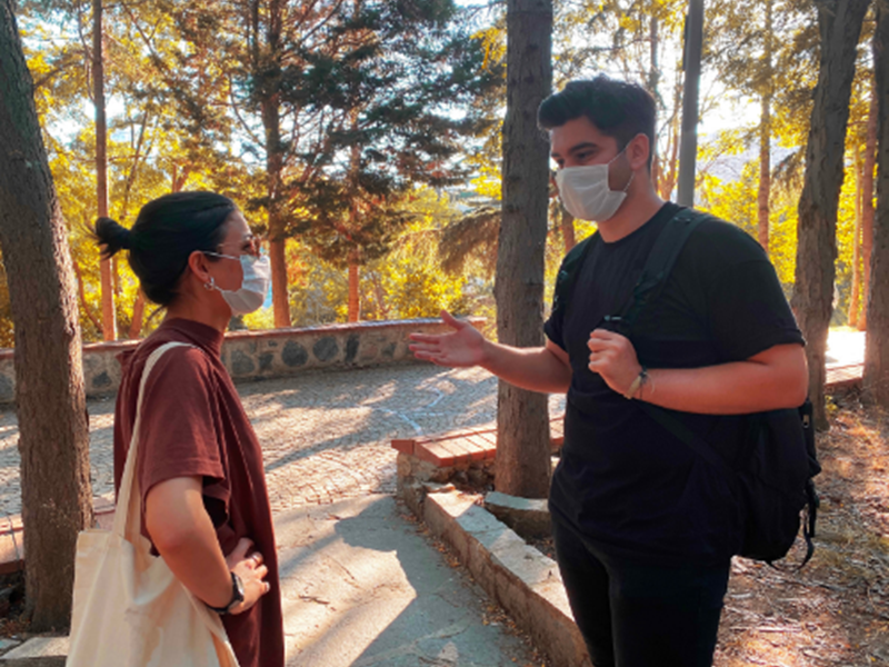 woman wearing face mask talking to man wearing face mask outdoors