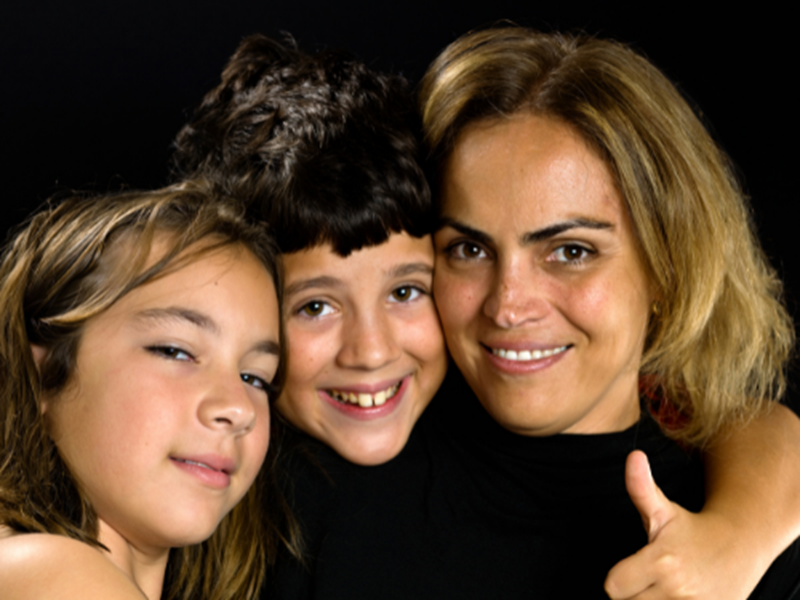 smiling woman with two smiling children, one with thumbs up